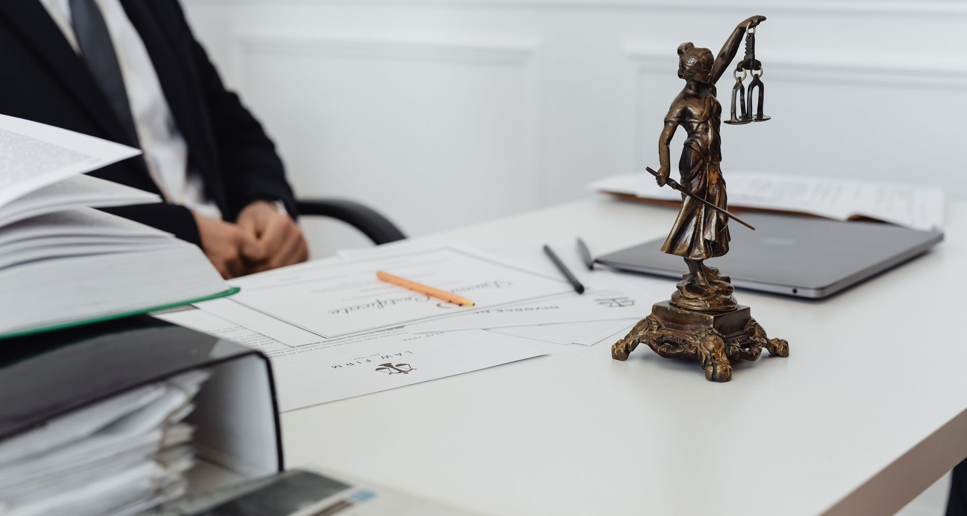 A legal professional's workspace featuring Lady Justice statue, documents, and a laptop.